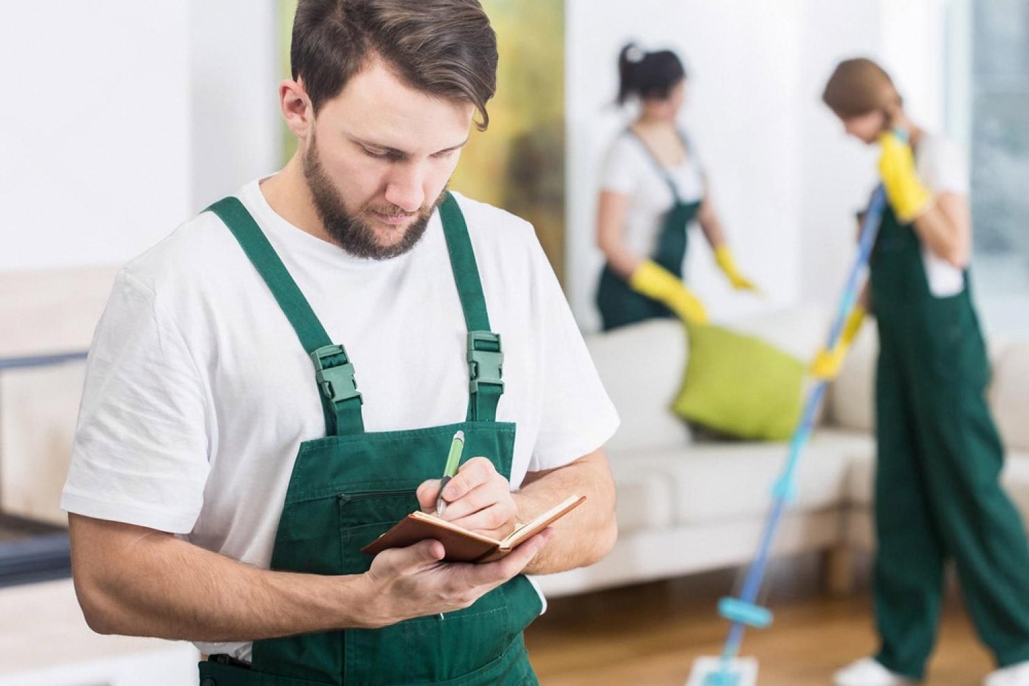 Home maintenance supervisor taking notes on a checklist while cleaners work in a Dubai villa