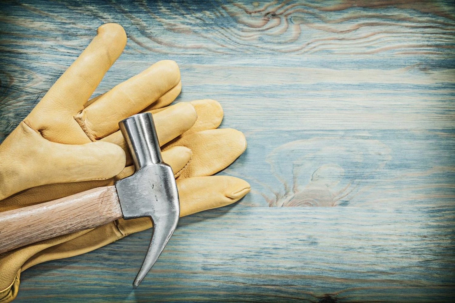 Leather work glove and claw hammer on a wooden surface, ready for home repairs in a Dubai apartment