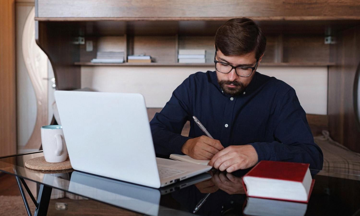 Adult learner in the UAE studying at home with a laptop and notebook during online exam preparation